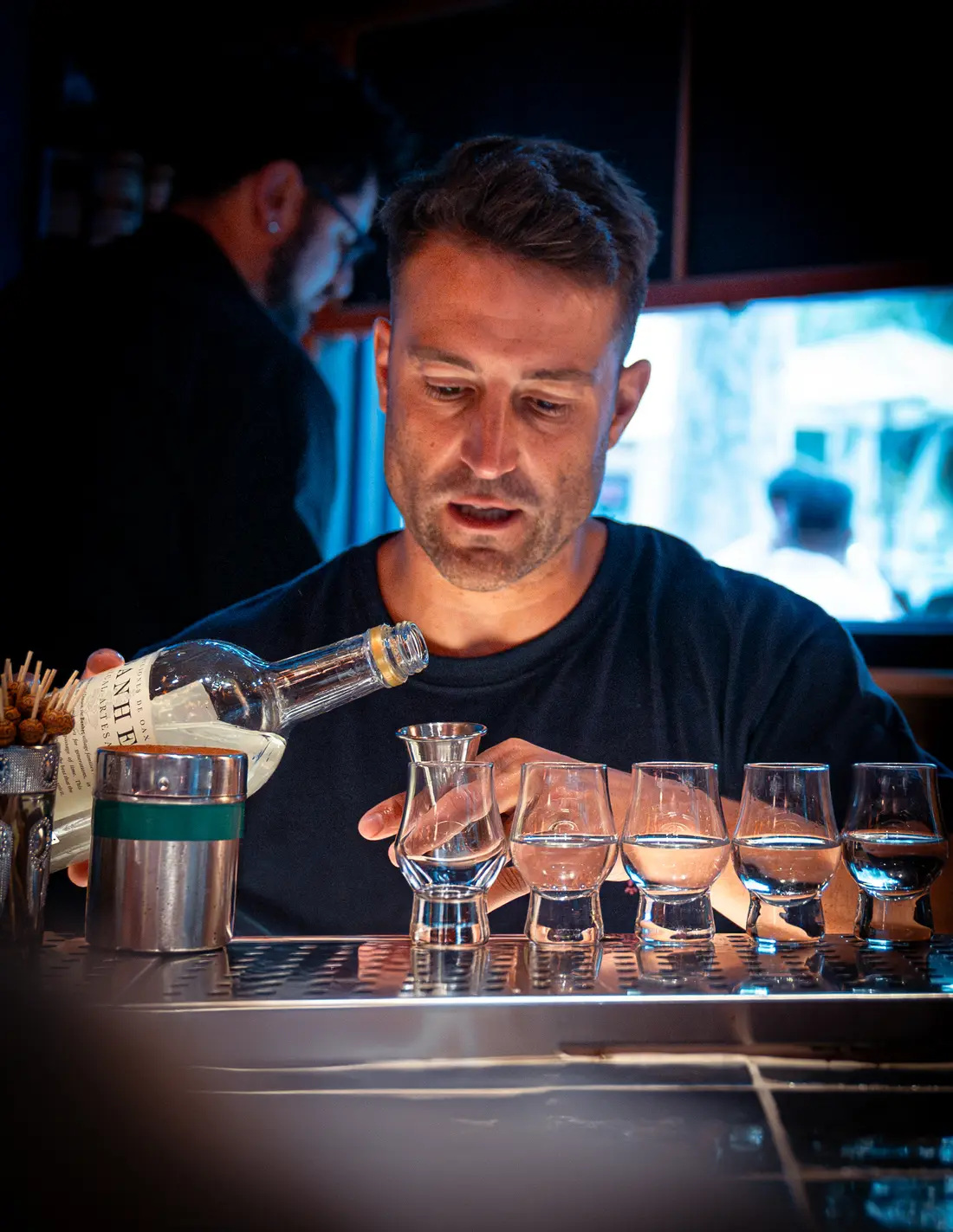 Bartender sirviendo mezcal en copitas para una cata de agave