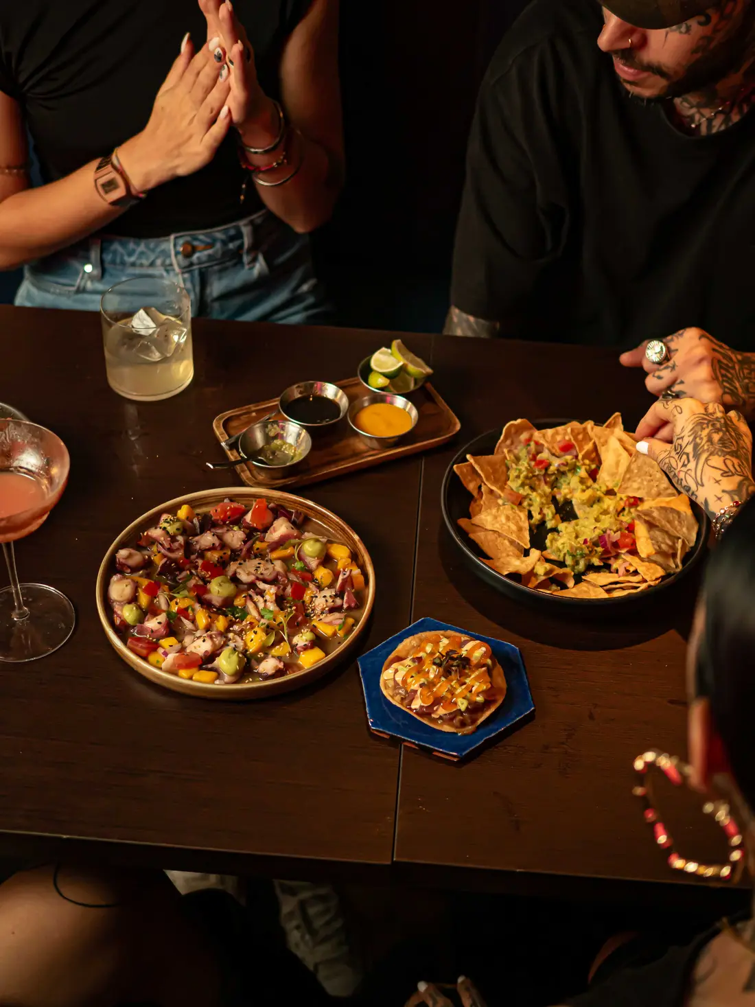 Mesa larga con platos mexicanos para compartir y un grupo de amigos
